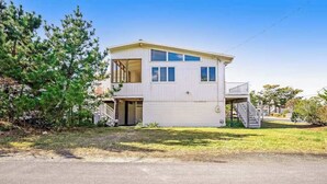 A two-story house with a garage, a balcony, and a staircase leading to the second floor. - Fenwick Island spacious beach house with deck, W/D & full kitchen - dog-friendly (Fenwick Island)