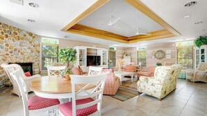 Ein geräumiges Wohnzimmer mit Steinwand, Kamin, Essbereich mit weißen Stühlen und einem großen Sofa.