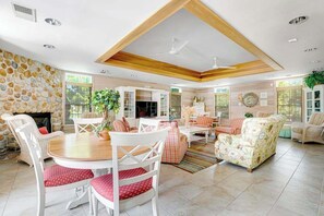 Ein geräumiges Wohnzimmer mit Steinwand, Kamin, Essbereich mit weißen Stühlen und einem großen Sofa.