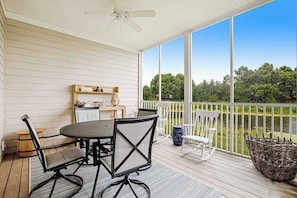 A covered patio with a table and chairs, a ceiling fan, and a view of greenery. - Bear Trap Dunes Lake View Condo w/ WiFi, Shared Pools, Tennis, & Gym - Dogs OK (Ocean View)