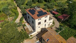 A two-story building with a tiled roof, solar panels, and a paved driveway. - Apartment 'La Casa Di Mia' in Piombino (Piombino)