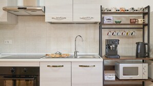 A modern kitchen with a built-in oven, a microwave, a coffee maker, and a shelf with mugs. - Apartment 'La Casa Di Mia' in Piombino (Piombino)