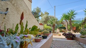 A garden with various potted plants, a brick pathway, and a metal fence. - Apartment 'La Casa Di Mia' in Piombino (Piombino)