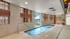 Una piscina con revestimiento de baldosas, un reloj en la pared y una ventana con vistas.