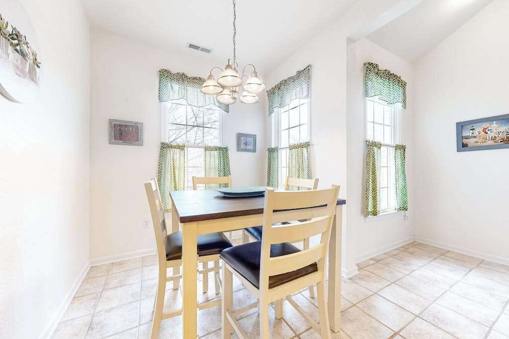 A dining area with a table and chairs, a chandelier, and patterned window treatments.
