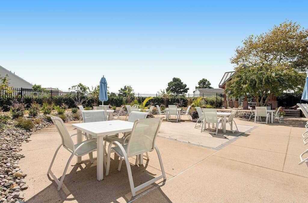 An outdoor patio area with tables and chairs, a covered seating area, and a fenced garden.