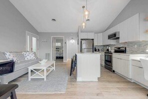 A modern kitchen with white cabinetry, a central island, and stainless steel appliances. - Newly renovated Sea Colony Tennis end condo with W/D, world-class tennis & pools (Bethany Beach)