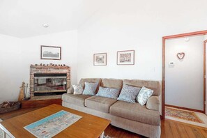 A living room with a sofa, a coffee table, a fireplace, and framed pictures on the wall. - Cat Hill house with free WiFi and canal access (Bethany Beach)