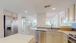 Una cocina moderna con refrigerador de acero inoxidable, lavavajillas y una isla grande con pileta.
