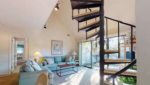 Ein modernes Wohnzimmer mit Treppe, Sofa, Couchtisch und einem Gemälde an der Wand.