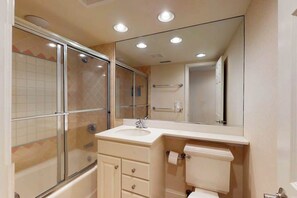 A bathroom with a glass shower enclosure, a sink, a toilet, and a large mirror. - Sea Colony 1st floor condo w/ pool, gym, and balcony - ocean view (Bethany Beach)