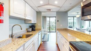 Una cucina moderna con piani in granito, elettrodomestici in acciaio inossidabile e vista all'esterno.
