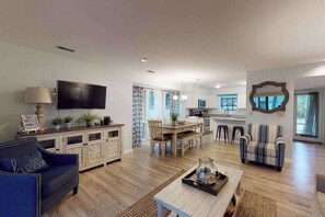 A spacious living area with a flat-screen TV, a dining table, and a kitchen in the background. - Sea Colony Tennis 1st floor condo w/ free WiFi, pool, and gym (Bethany Beach)
