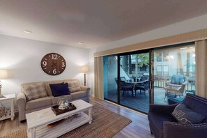 A living room with a sofa, coffee table, and a large wall clock. - Sea Colony Tennis 1st floor condo w/ free WiFi, pool, and gym (Bethany Beach)
