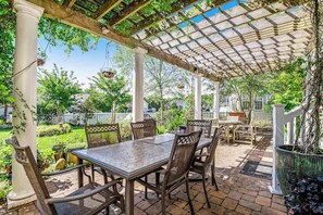 A covered patio area with a table and chairs, surrounded by white columns and a pergola. - Bayview Landing home with central AC, shared pool, washer/dryer, & free WiFi (Selbyville)