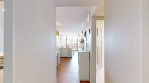 A narrow hallway leading to a kitchen with white cabinets and a dining area with a table and chairs. - Sea Colony Oceanside Condo Steps to Private Beach, Pools and Tennis (Bethany Beach)