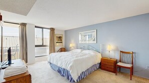 A bedroom with a bed, bedside tables, a chair, a desk with a computer, and a window with curtains. - Sea Colony Oceanside Condo Steps to Private Beach, Pools and Tennis (Bethany Beach)