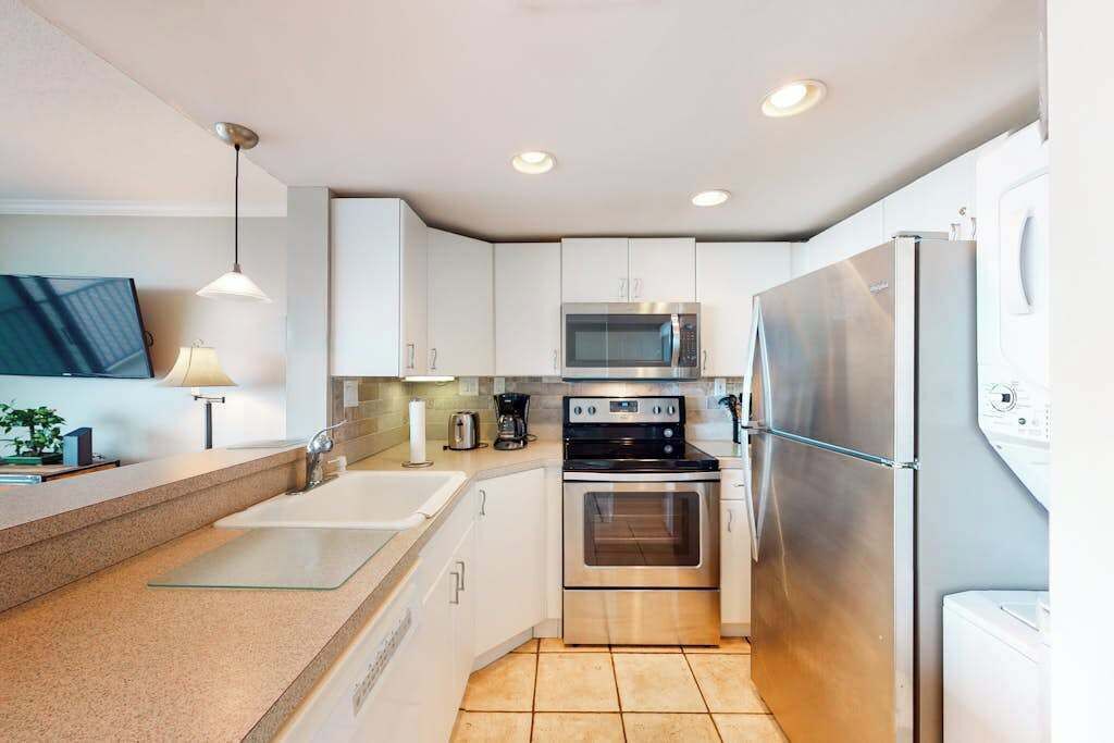 A modern kitchen with white cabinets, stainless steel appliances, a double sink, and a built-in oven.