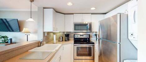 A modern kitchen with white cabinets, stainless steel appliances, a double sink, and a built-in oven.