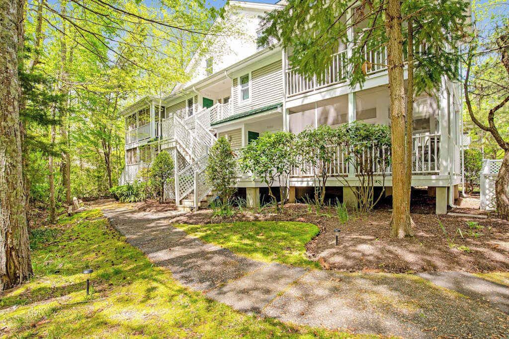 A two-story house with a porch, surrounded by trees.