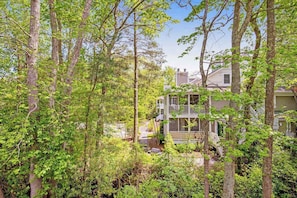 A two-story house surrounded by dense trees.