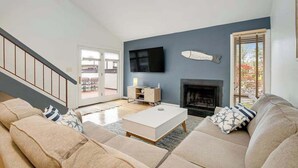 Una sala de estar con sofá, mesa de centro, televisor, chimenea y una escalera.