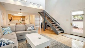 Una sala de estar moderna con un sofá, una mesa de centro y una escalera que lleva a un balcón.