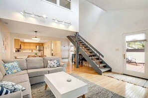 Ein modernes Wohnzimmer mit einer Couch, einem Couchtisch und einer Treppe, die auf einen Balkon führt.