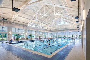 An indoor swimming pool with a high ceiling and large windows. - Bayside Condo w/ Balcony & Amazing Shared Pools, Hot Tub, Golf, Tennis, Fitness (Selbyville)