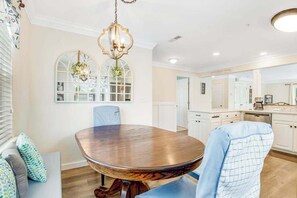 A dining area with a round wooden table, blue chairs, and a chandelier.