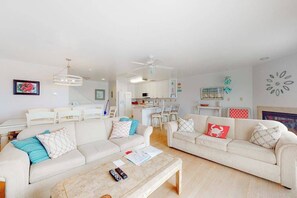 Ein modernes Wohnzimmer mit zwei Sofas, einem Couchtisch und einem Essbereich im Hintergrund.