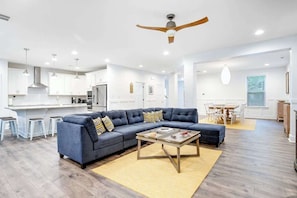 A modern living room with a sectional sofa, a coffee table, and a ceiling fan. - Bethany West Retreat W/ Shared Pool, Free WiFi, Full Kitchen & Ideal Location (Bethany Beach)