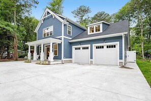 Une maison à deux étages avec un garage, une véranda et une allée.