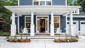 Een huis met twee verdiepingen, een veranda, witte zuilen en een voordeur.