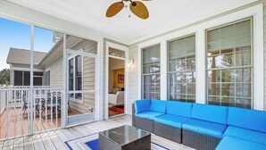 A covered porch with a blue sofa, a glass coffee table, and a ceiling fan. - Wonderful Bear Trap Dunes Townhouse w/Free WiFi, Shared Pool, Deck, W/D, & AC (Ocean View)