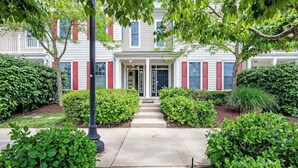 A two-story building with a central entrance, surrounded by well-maintained greenery and a concrete pathway leading to the door. - Wonderful Bear Trap Dunes Townhouse w/Free WiFi, Shared Pool, Deck, W/D, & AC (Ocean View)