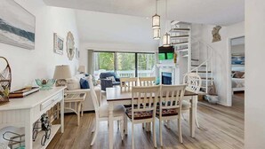 A spacious living area with a dining table, chairs, and a staircase. - Sea Colony Tennis 2nd Floor Condo W/ Loft, Free WiFi, Balcony & Shared Pools (Bethany Beach)