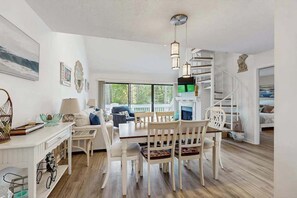 Een ruime woonkamer met een eettafel, stoelen en een trap.
