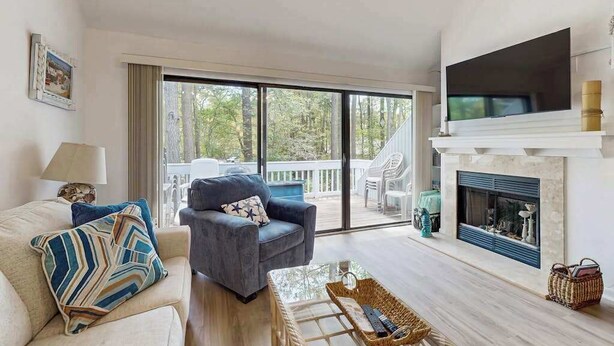 A living room with a sofa, armchair, fireplace, and a large window. - Sea Colony Tennis 2nd Floor Condo W/ Loft, Free WiFi, Balcony & Shared Pools (Bethany Beach)