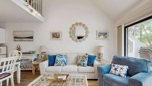 A living room with a sofa, a blue armchair, a coffee table, and a mirror on the wall. - Sea Colony Tennis 2nd Floor Condo W/ Loft, Free WiFi, Balcony & Shared Pools (Bethany Beach)