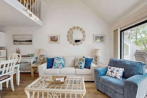 Een woonkamer met een bank, een blauwe fauteuil, een salontafel en een spiegel aan de muur.