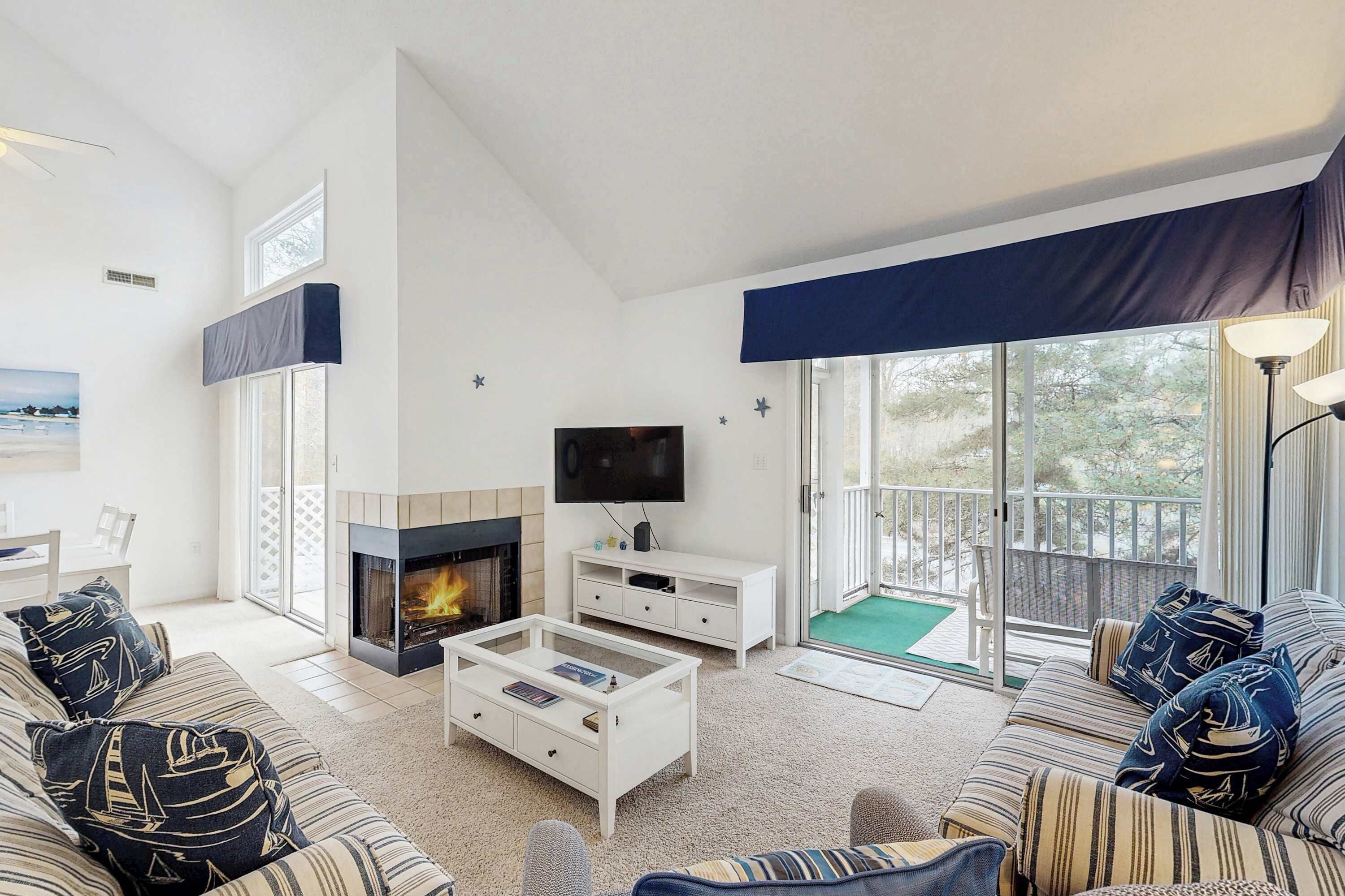 Un salon avec une cheminée, un canapé, une table basse, un téléviseur et un balcon offrant une vue agréable.