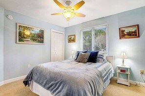 A bedroom with a bed, a ceiling fan, a window, and wall-mounted artwork. - Bayberry Woods condo W/ shared pool, high-speed WiFi & central AC - near beach (Bethany Beach)
