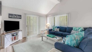 A living room with a TV, sofa, and a sign reading 'Beach House.' - 2-Story Sea Colony Condo w/Bikes, Fireplace, Shared Pools, Gym, Sauna, & Tennis (Bethany Beach)