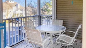 A balcony with a round table and white chairs, overlooking a parking area and houses. - 2-Story Sea Colony Condo w/Bikes, Fireplace, Shared Pools, Gym, Sauna, & Tennis (Bethany Beach)