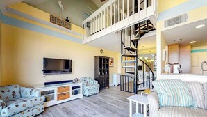 Ein Wohnzimmer mit Sofa, Fernseher und einer Treppe.