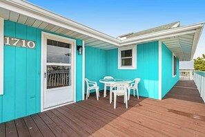 A turquoise building with a number '1710' on the door, a deck with white chairs, and a small table. - Dog-friendly town of Fenwick home with guest suite, WiFi, & elevator (Fenwick Island)
