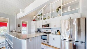A modern kitchen with white cabinetry, stainless steel appliances, and a central island. - Sandpiper Village home with private beach, fireplace, balcony, & washer/dryer (South Bethany)