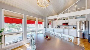 A modern kitchen with a large island, stainless steel appliances, and a view through large windows. - Sandpiper Village home with private beach, fireplace, balcony, & washer/dryer (South Bethany)