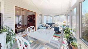 Una habitación iluminada por el sol con una mesa de comedor, sillas, un sofá y un ventilador de techo.